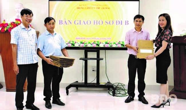 Cán bộ, nhân viên Trung tâm Lưu trữ lịch sử tỉnh nhận bàn giao lại 43 hồ sơ đi B từ đại diện Phòng Nội vụ TP Quy Nhơn (bìa phải). Ảnh: H.THU